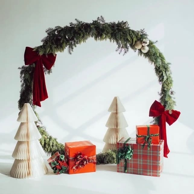 Christmas mini session set: a greenery wreath with red velvet bows, white paper trees, and wrapped gifts