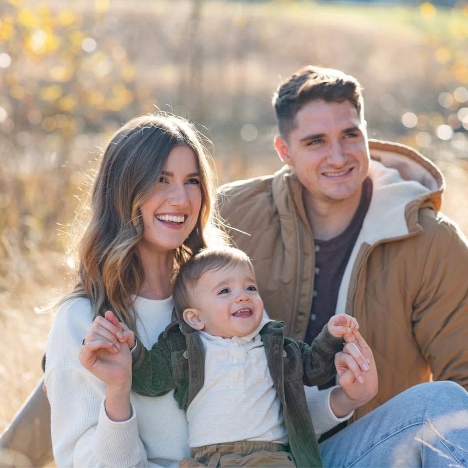 Family of three sitting together in a golden field