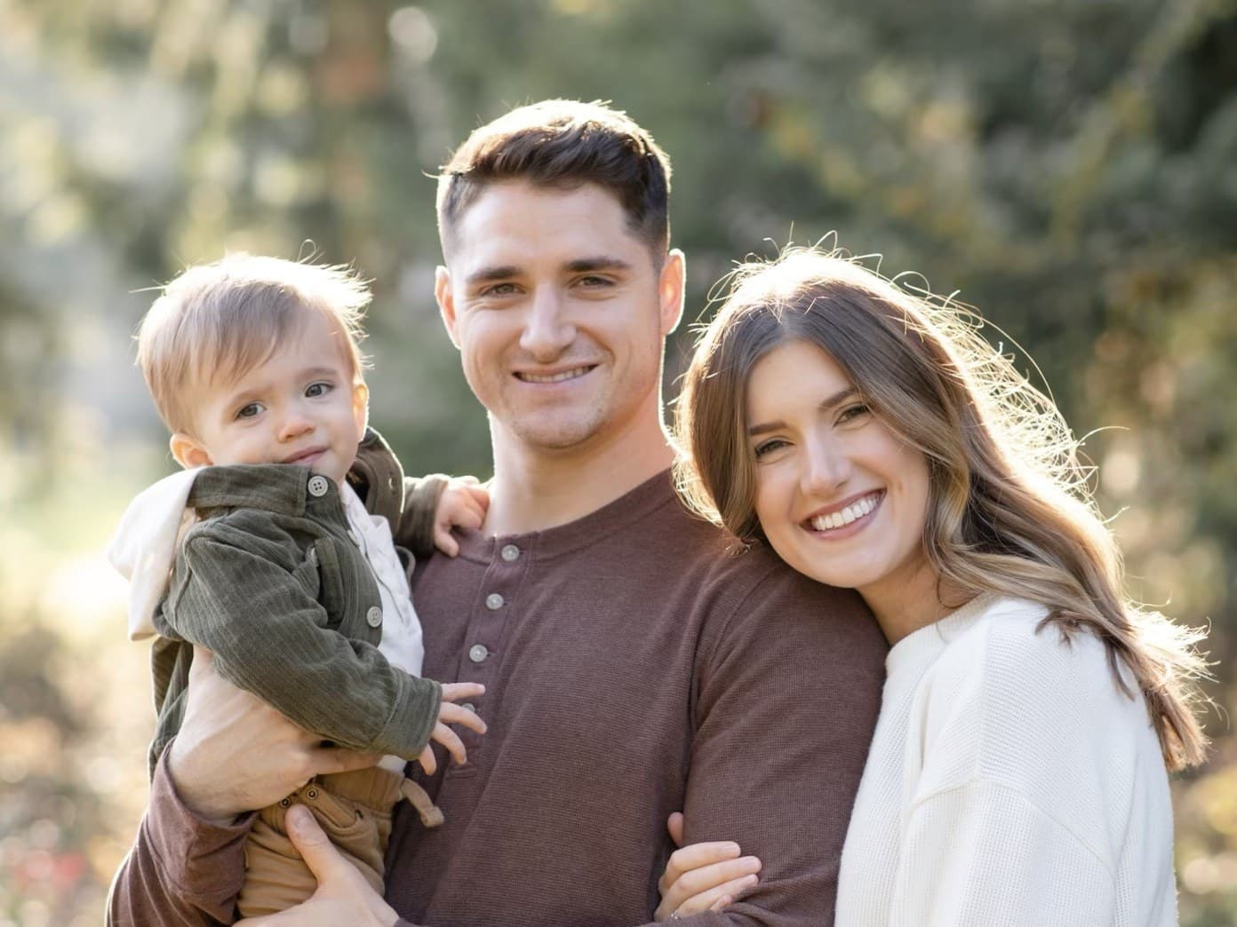 Outdoor family portrait of parents and a toddler in golden hour light