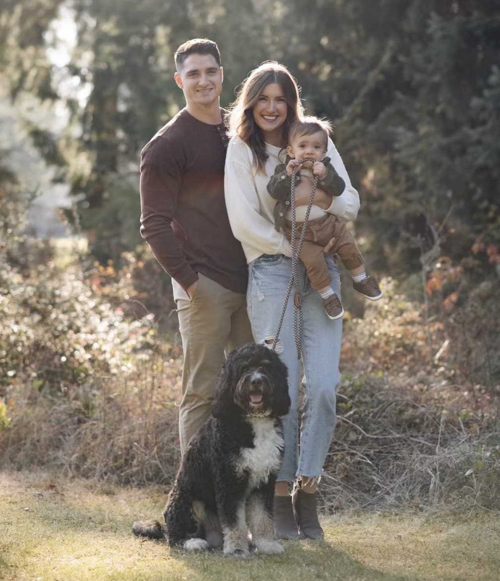 Family with their toddler and a fluffy dog outdoors