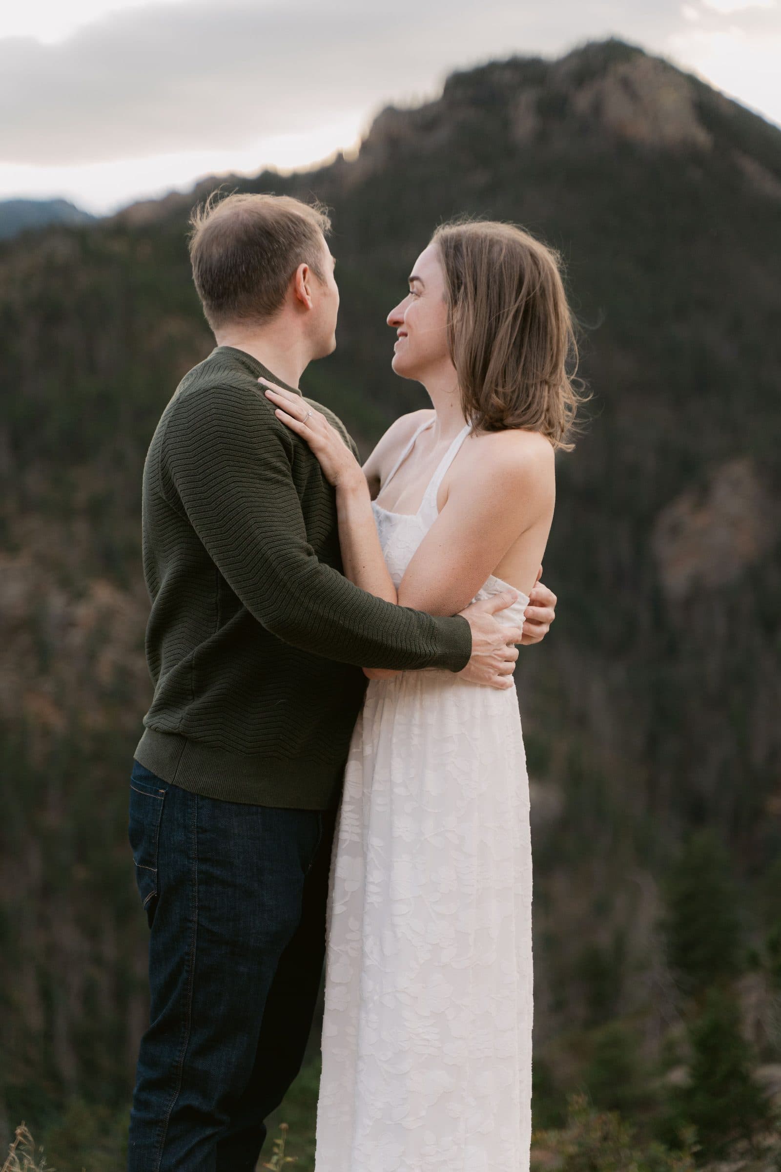 Couple holding each other with a mountain ridge behind them