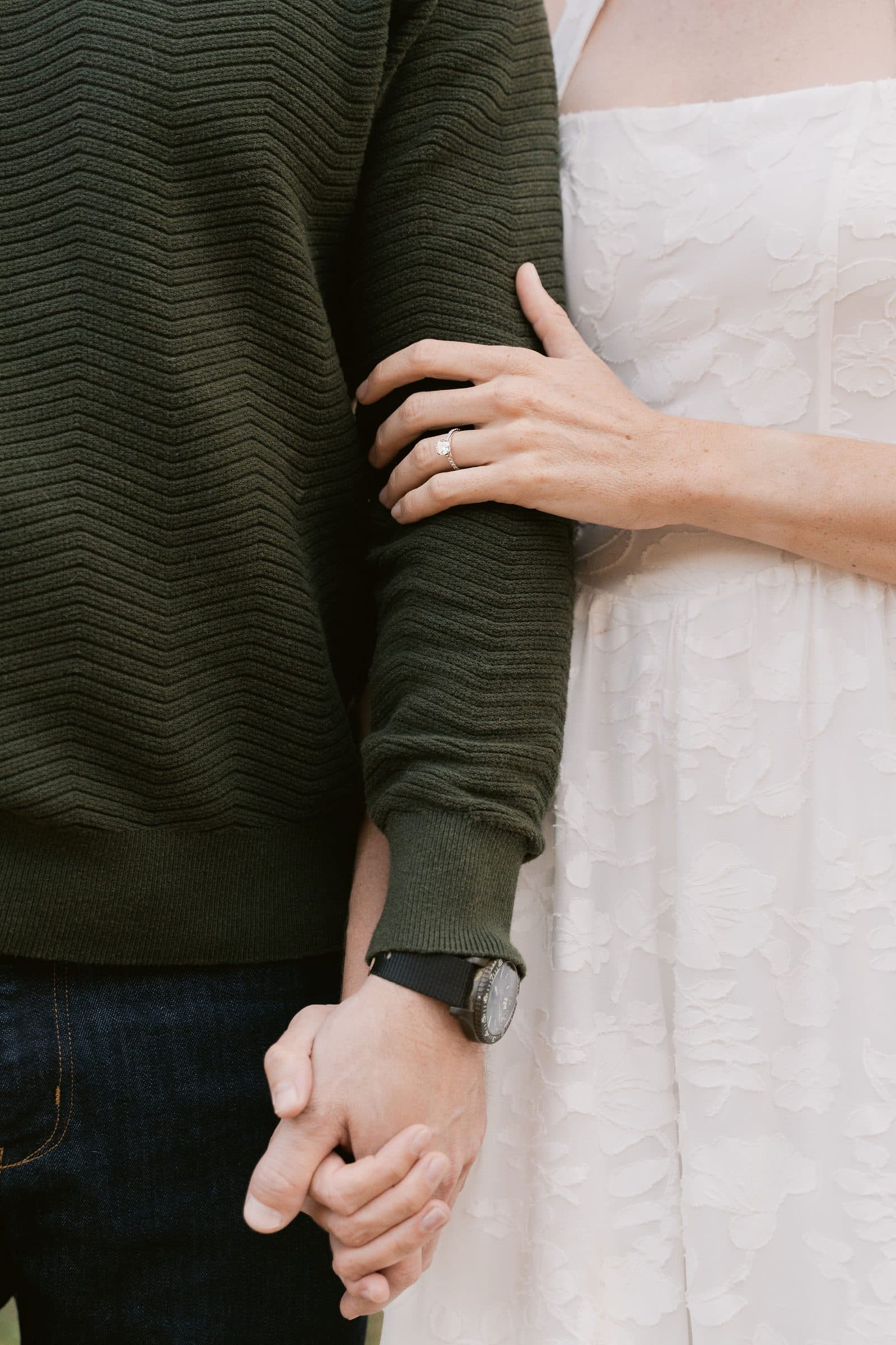 Close-up of a woman's hand with a ring resting on her partner's arm