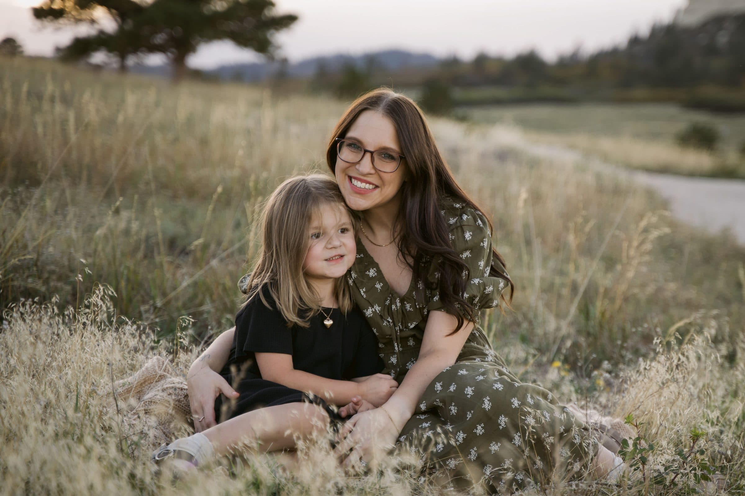 Mother and daughter sitting together in golden grass