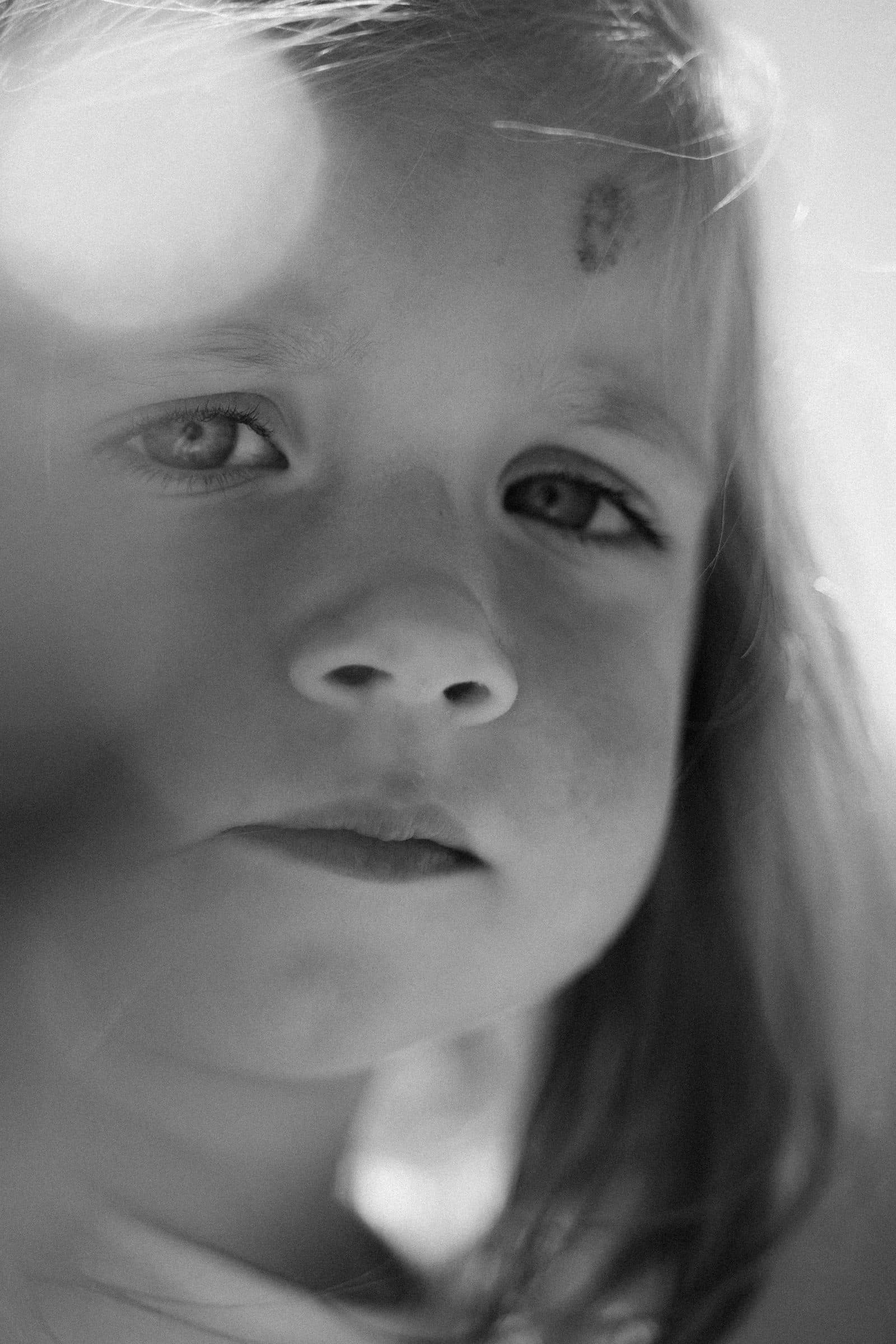 Soft black and white close-up of a little girl's face in hazy sunlight