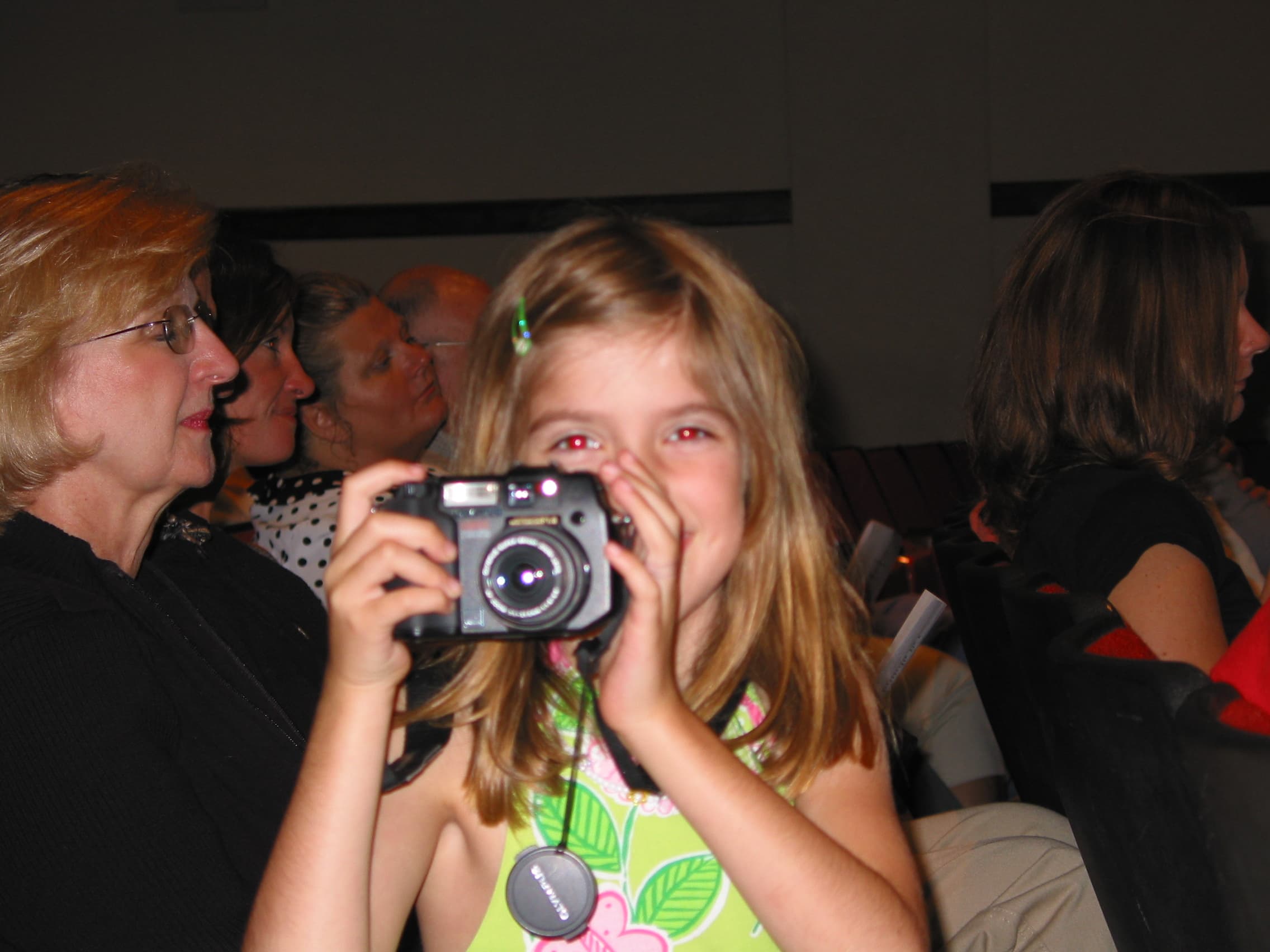 Olivia as a little girl, holding a black Olympus camera up to her eye