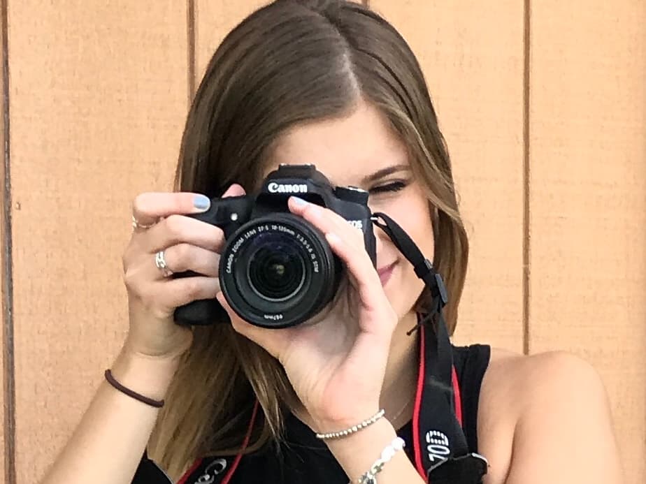 Olivia now, a Canon camera raised to her eye