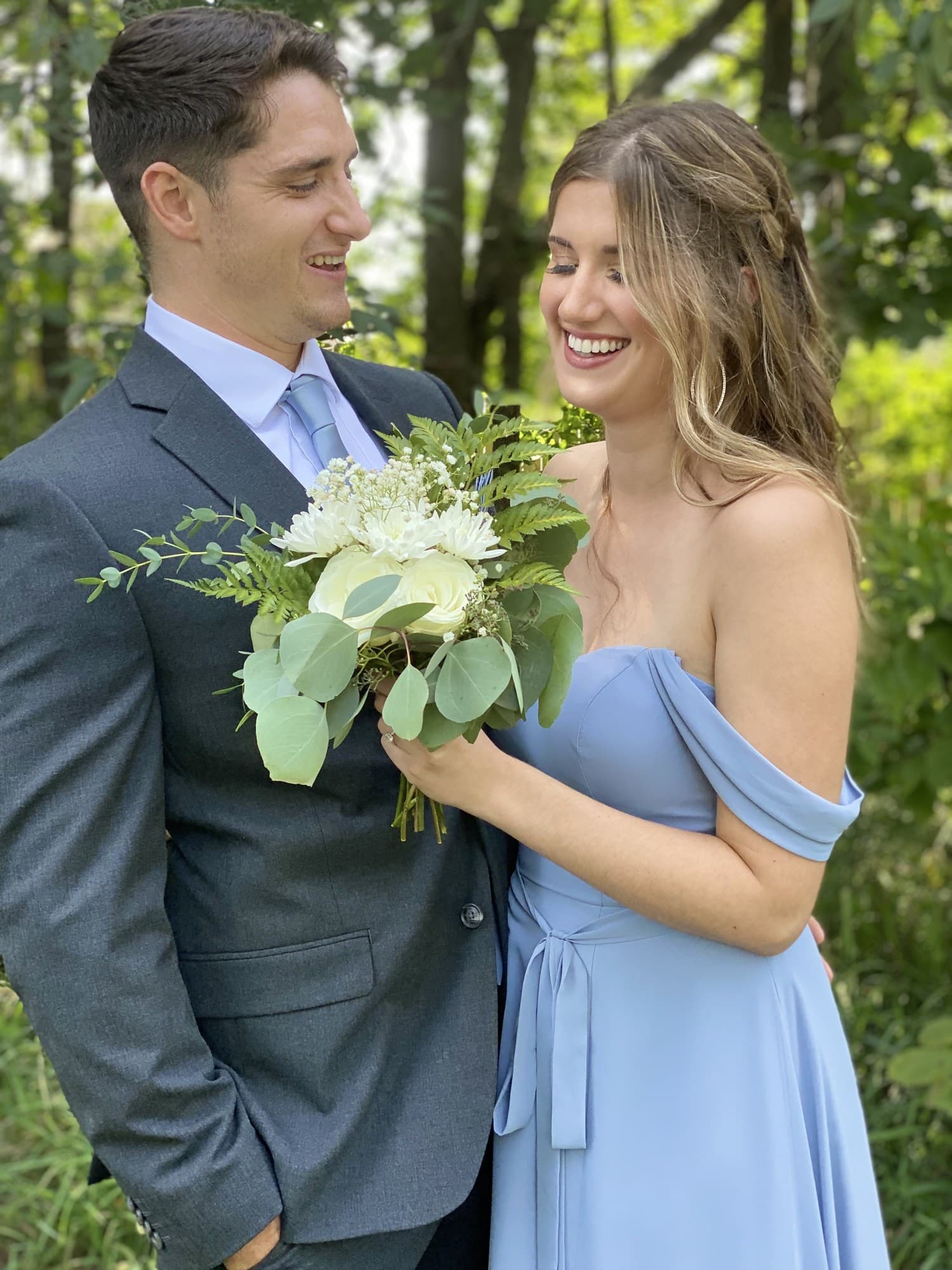 Couple in a garden sharing a look, light blue dress and charcoal suit