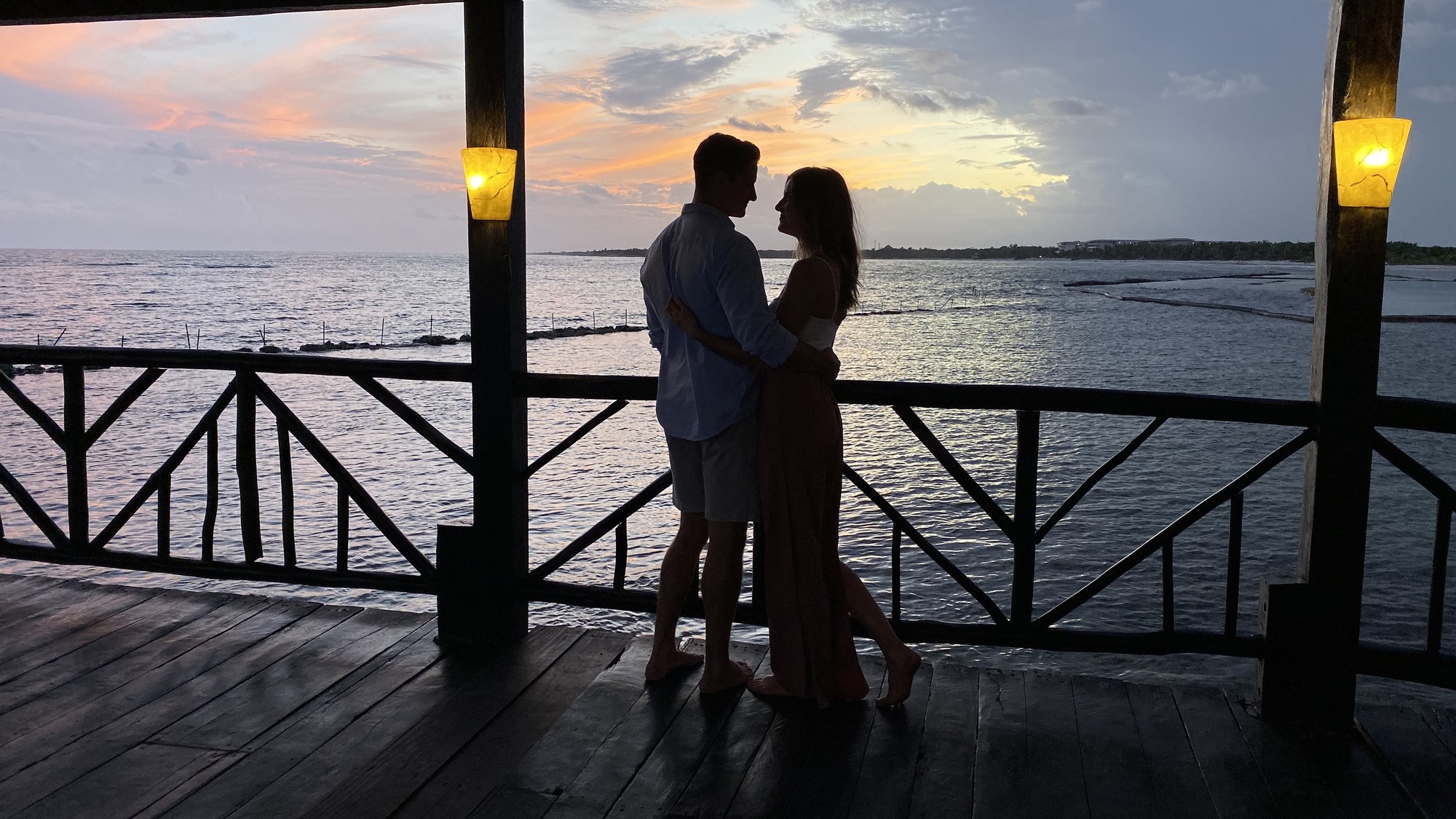 A couple embracing on a wooden balcony at sunset
